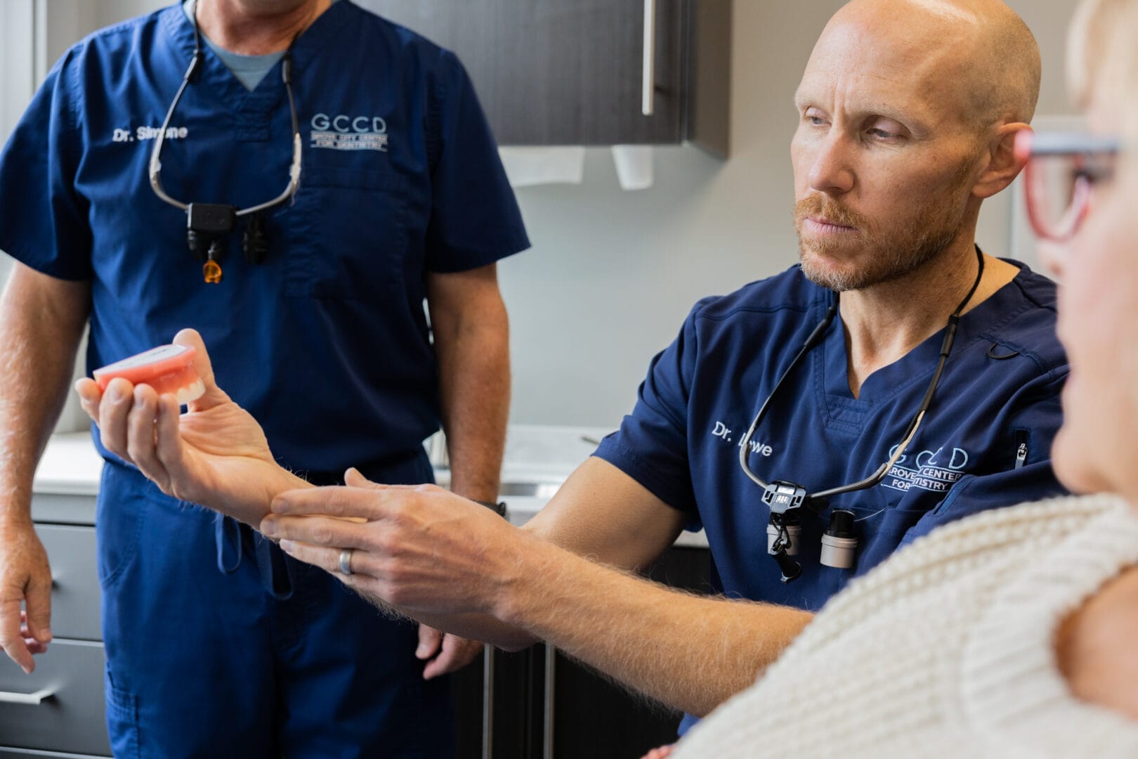 Dr. Kyle Lowe holding a gum model and explaining gum grafting to a patient